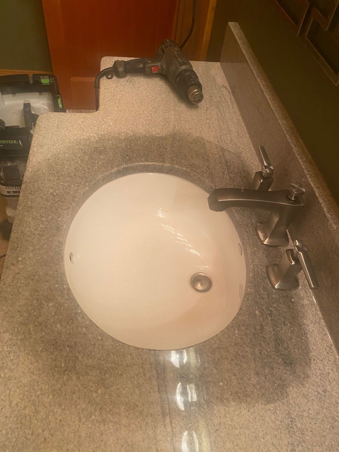 Bathroom sink with chrome faucet and granite countertop beside a brown wall cabinet.