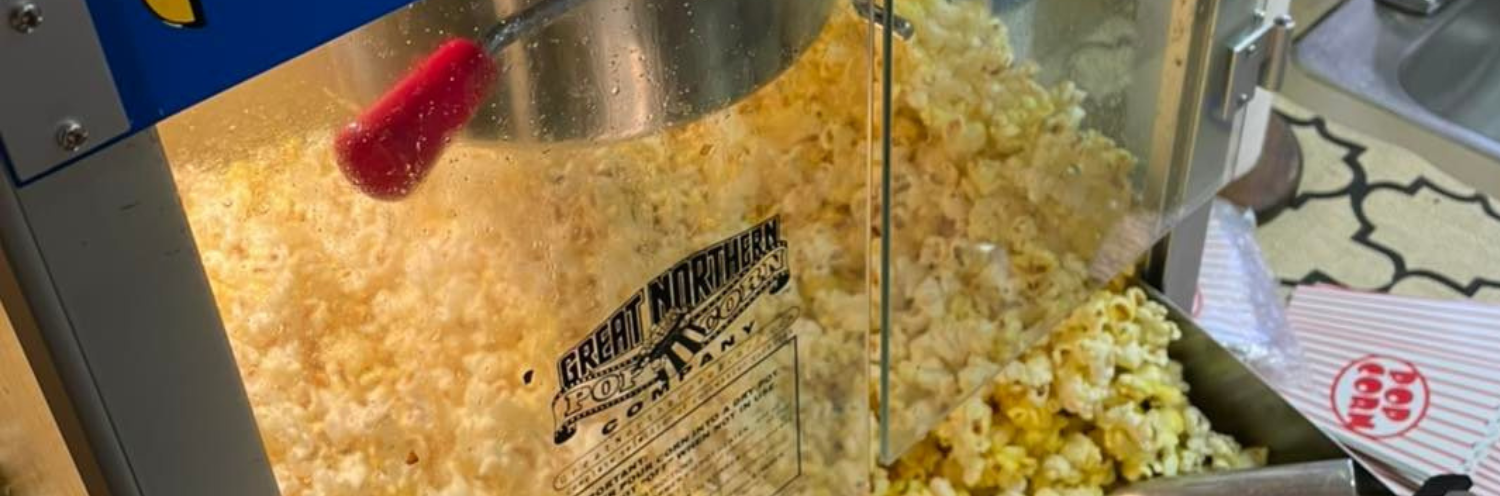 Popcorn machine with yellow popcorn popping in a stainless steel kettle and glass case