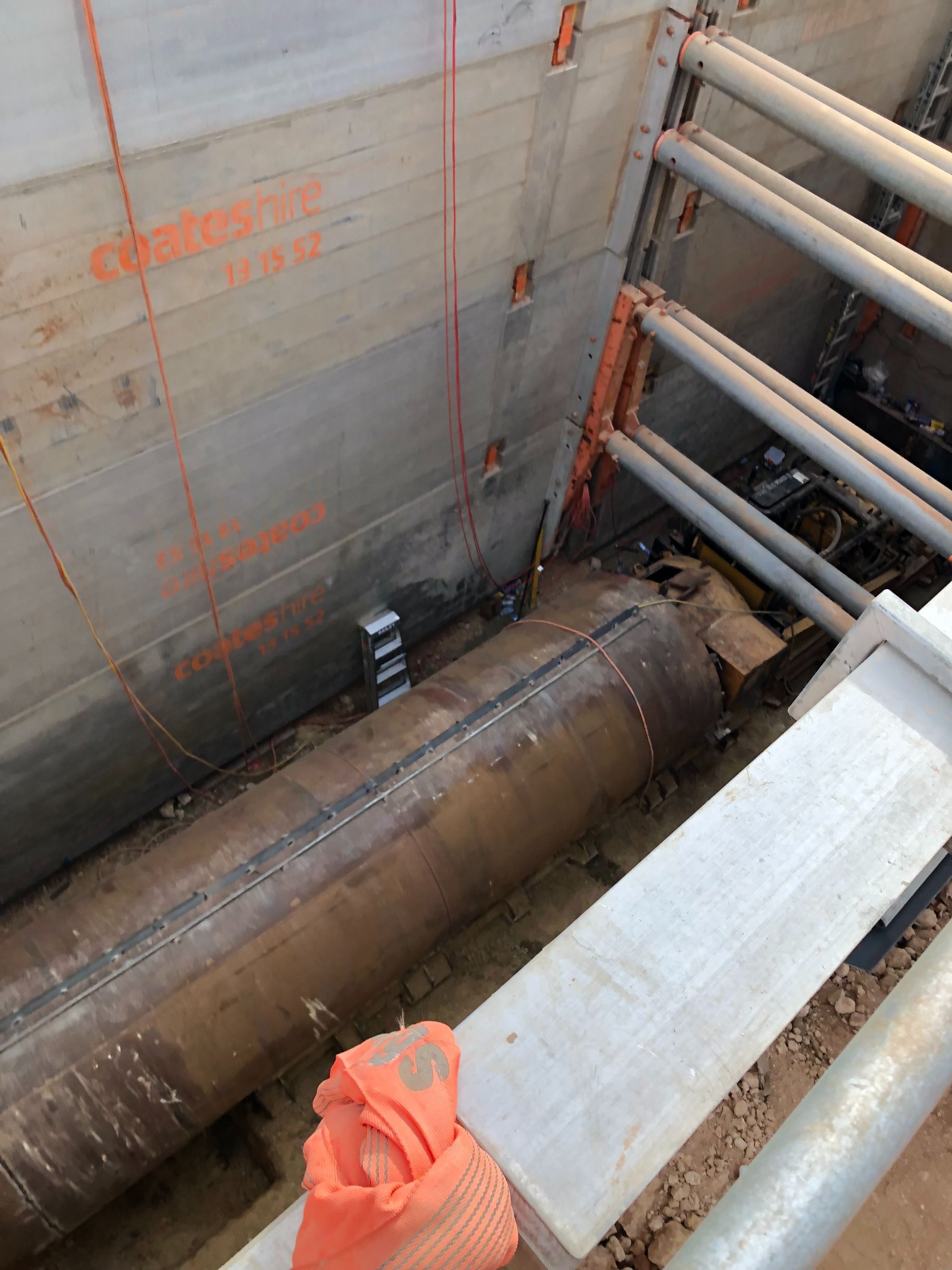 A person is standing next to a large pipe in a trench.