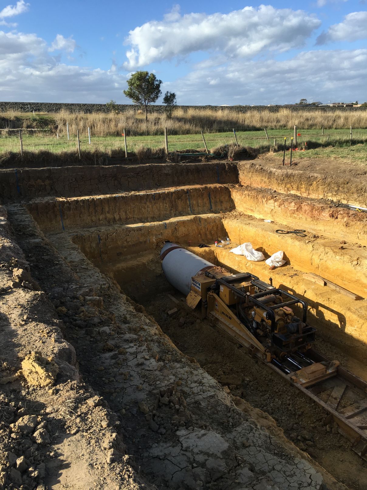 A large pipe is sitting in the middle of a dirt field.