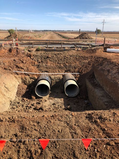Two pipes are sitting in the dirt on a construction site.