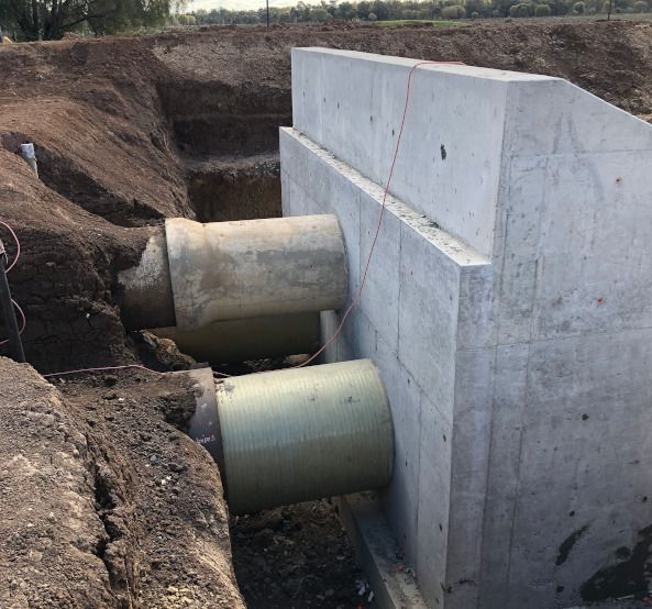 A concrete wall with a bunch of pipes coming out of it