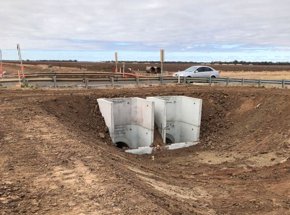 A car is driving down a dirt road next to a large hole in the ground.