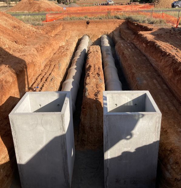A couple of concrete blocks in a dirt area with pipes in the background