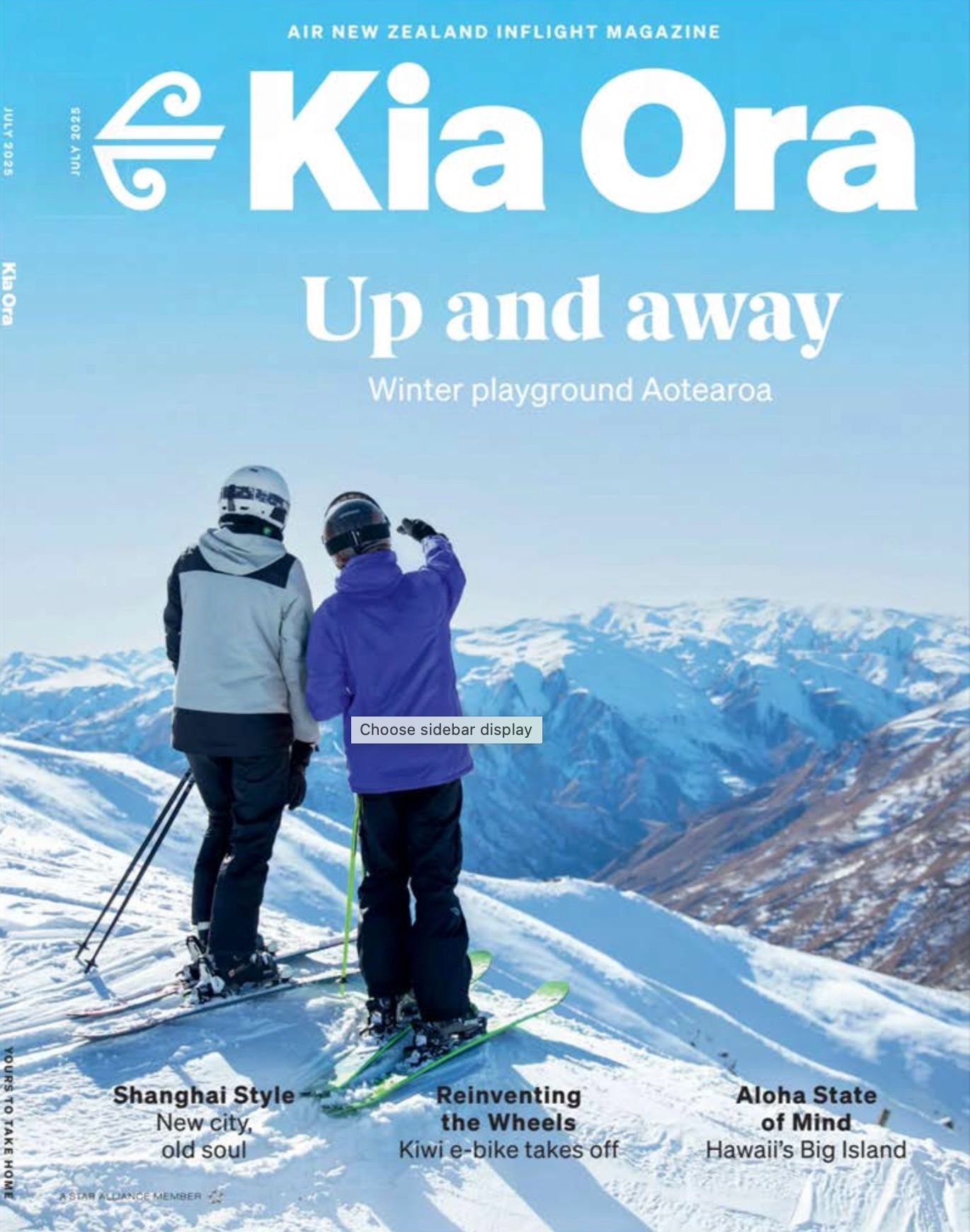 Two skiers on a snowy mountaintop, looking at a mountain range. Kia Ora magazine cover.