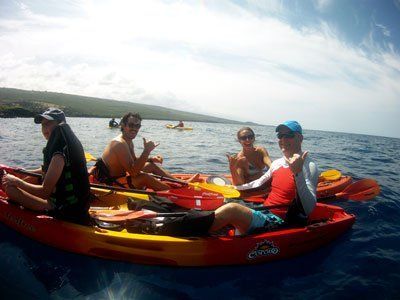 People in kayaks on ocean, sunny day. Some people making hand gestures.