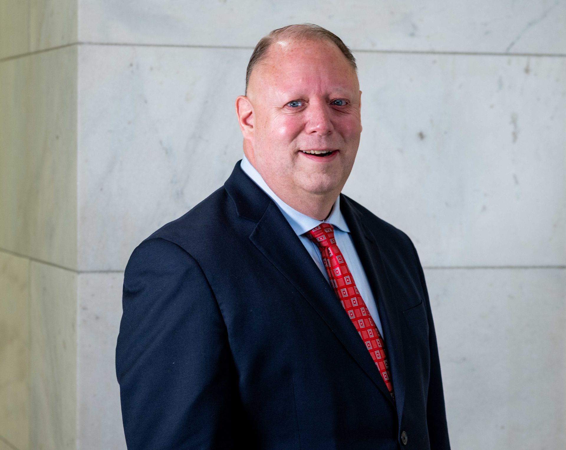 Scott Greenlee in a suit and tie is smiling for the camera