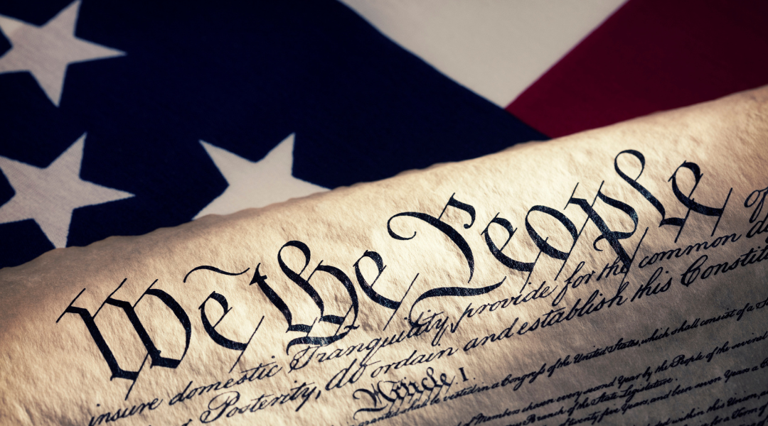 A copy of the united states constitution is sitting in front of an american flag.