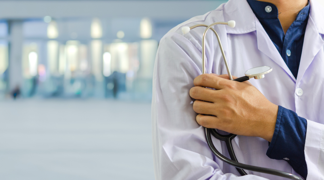 A doctor is holding a stethoscope over his shoulder in a hospital.