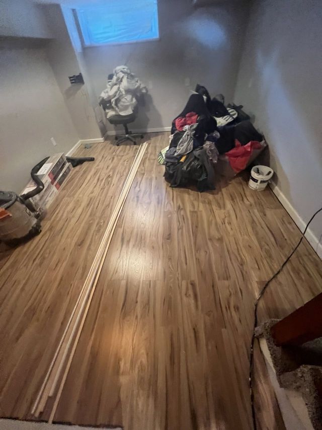 Plank flooring going down in a finished lower level, a Handyman on Demand basement project