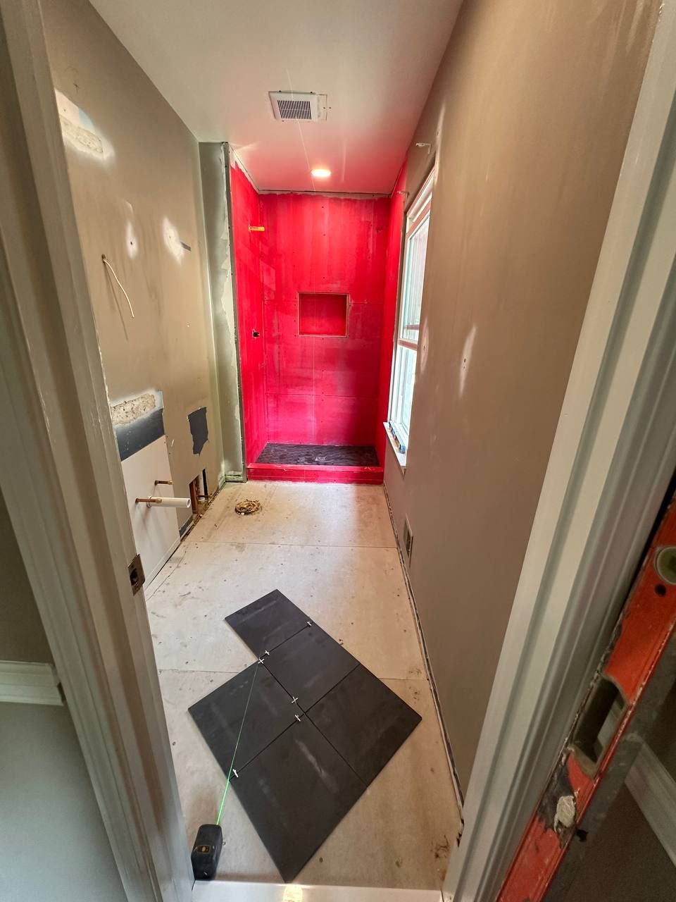 Waterproofed walk-in shower with niche and black floor tile layout in an Elkridge, MD bathroom remodel