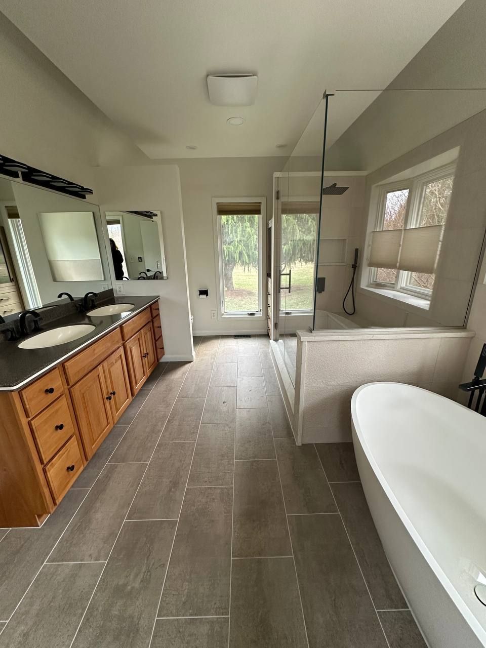 Local bathroom remodel in Clarksville MD with double sink vanity, dark granite countertop, frameless glass shower, and freestanding soaking tub by licensed contractor Handyman on Demand
