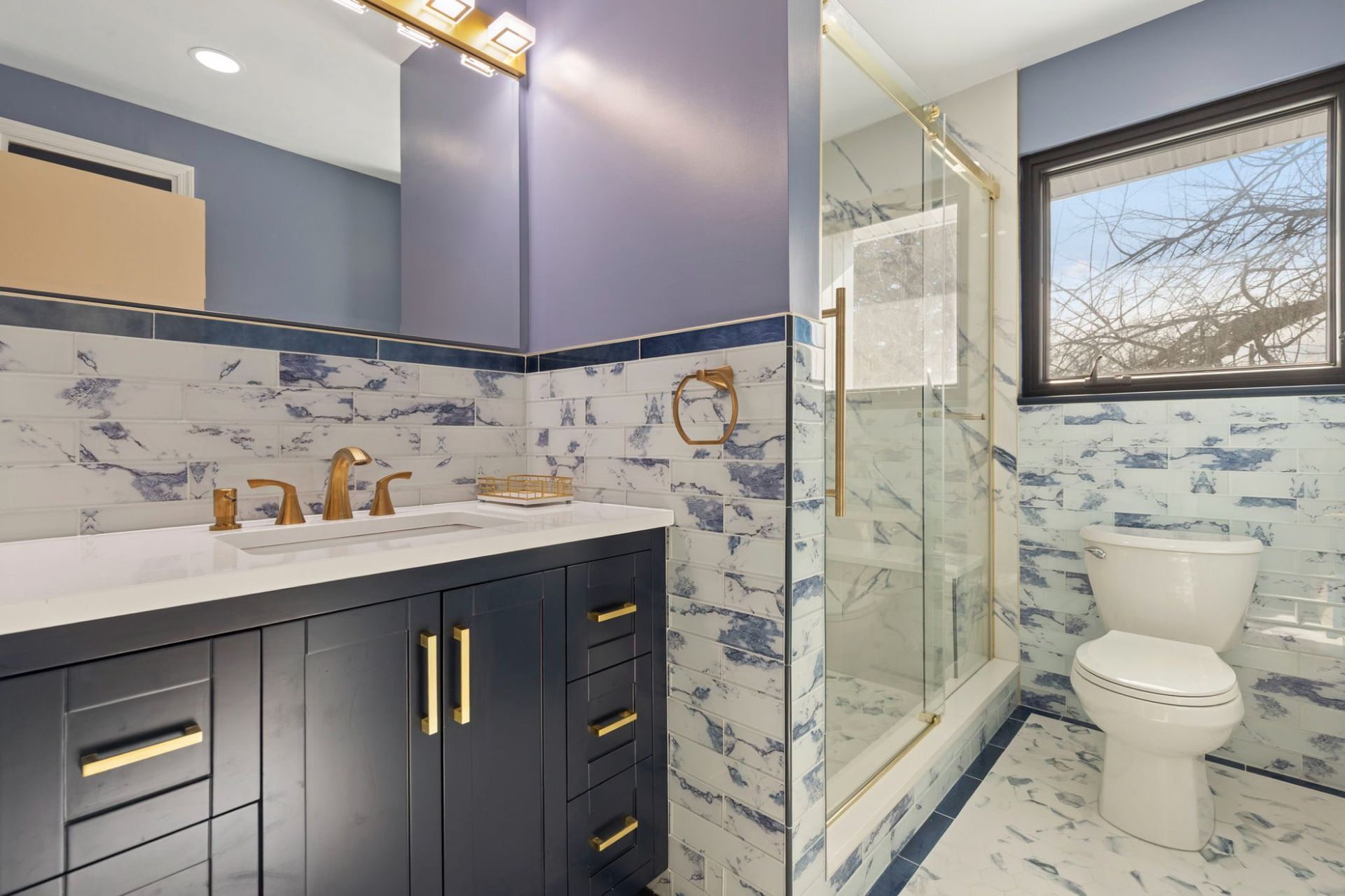 Full bathroom remodel overview with vanity, walk-in shower, toilet, and marble tile by professional remodeling contractor Handyman on Demand serving Clarksville MD