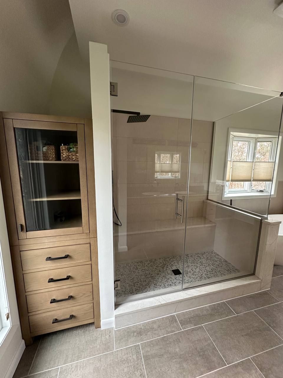 Licensed bathroom remodeling contractor in Clarksville MD — frameless glass shower enclosure, built-in linen storage cabinet, and pebble stone shower floor by Handyman on Demand