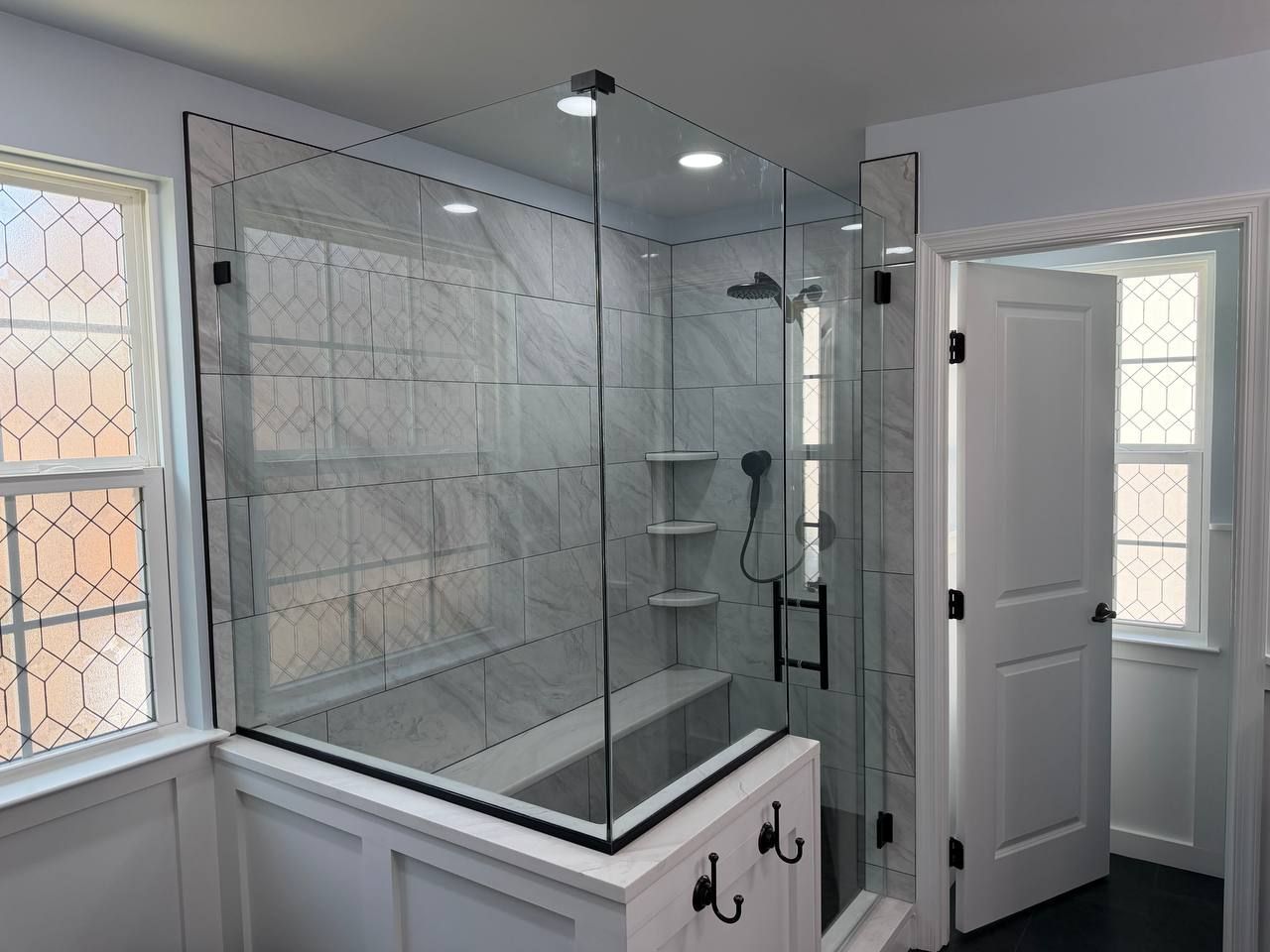 Professional bathroom renovation and remodel in Clarksville Maryland with glass shower enclosure, white marble tile, recessed ceiling lighting, and matte black hardware by Handyman on Demand