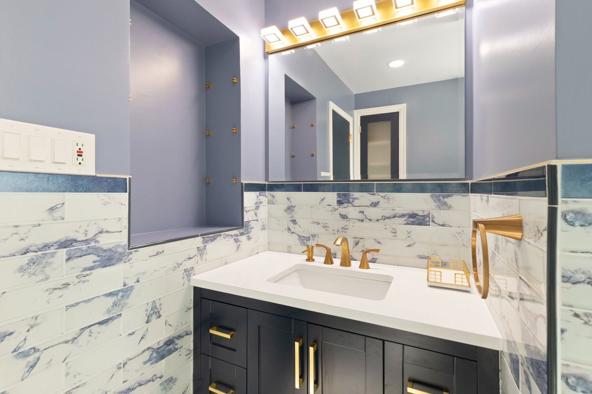 Bathroom renovation featuring new vanity, gold light bar, built-in wall niche, and marble tile by licensed remodeling contractor Handyman on Demand serving Clarksville MD