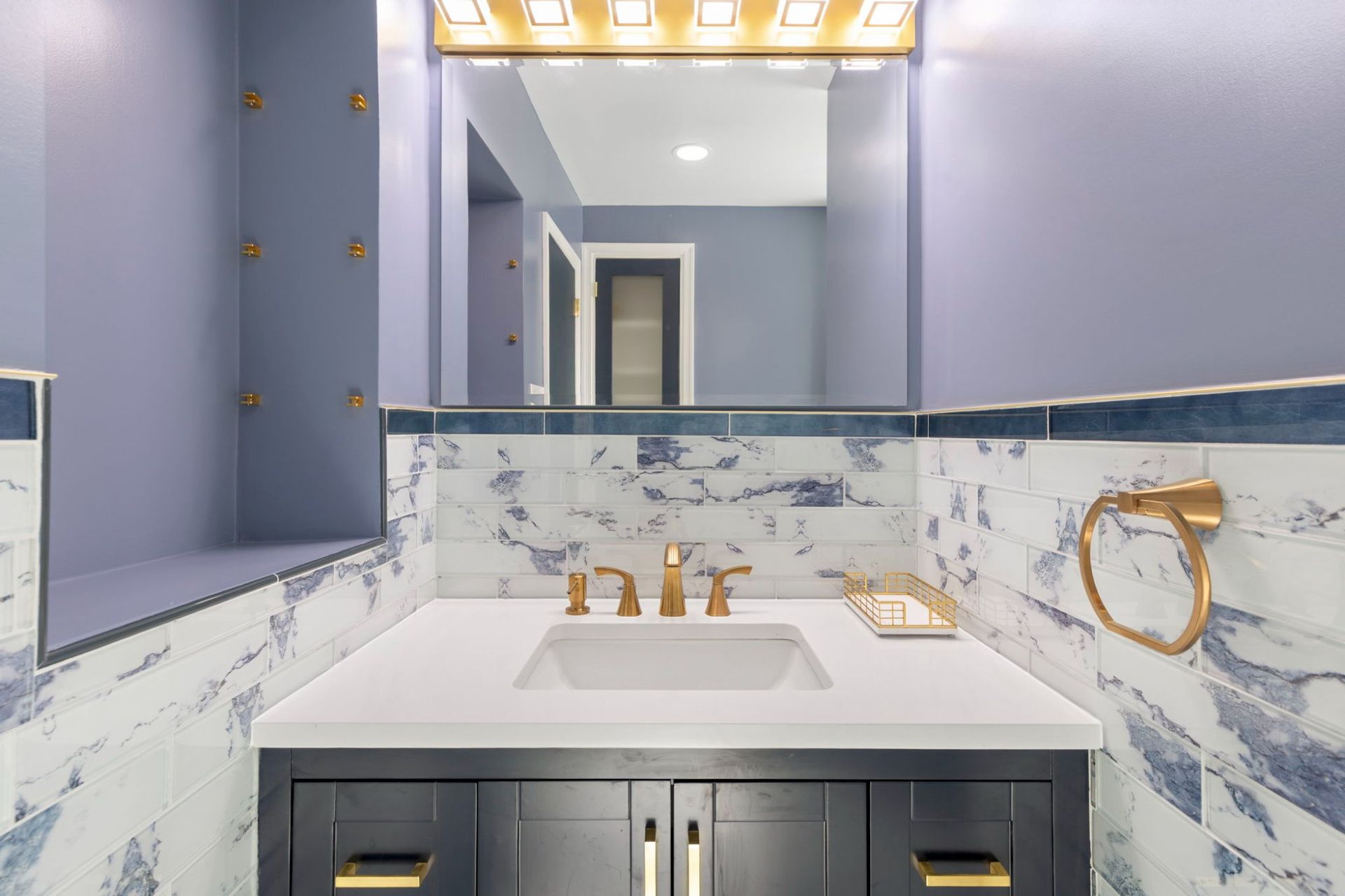 Bathroom vanity remodel with undermount sink, framed mirror, brushed gold light fixture, and marble tile by professional contractor Handyman on Demand serving Clarksville MD