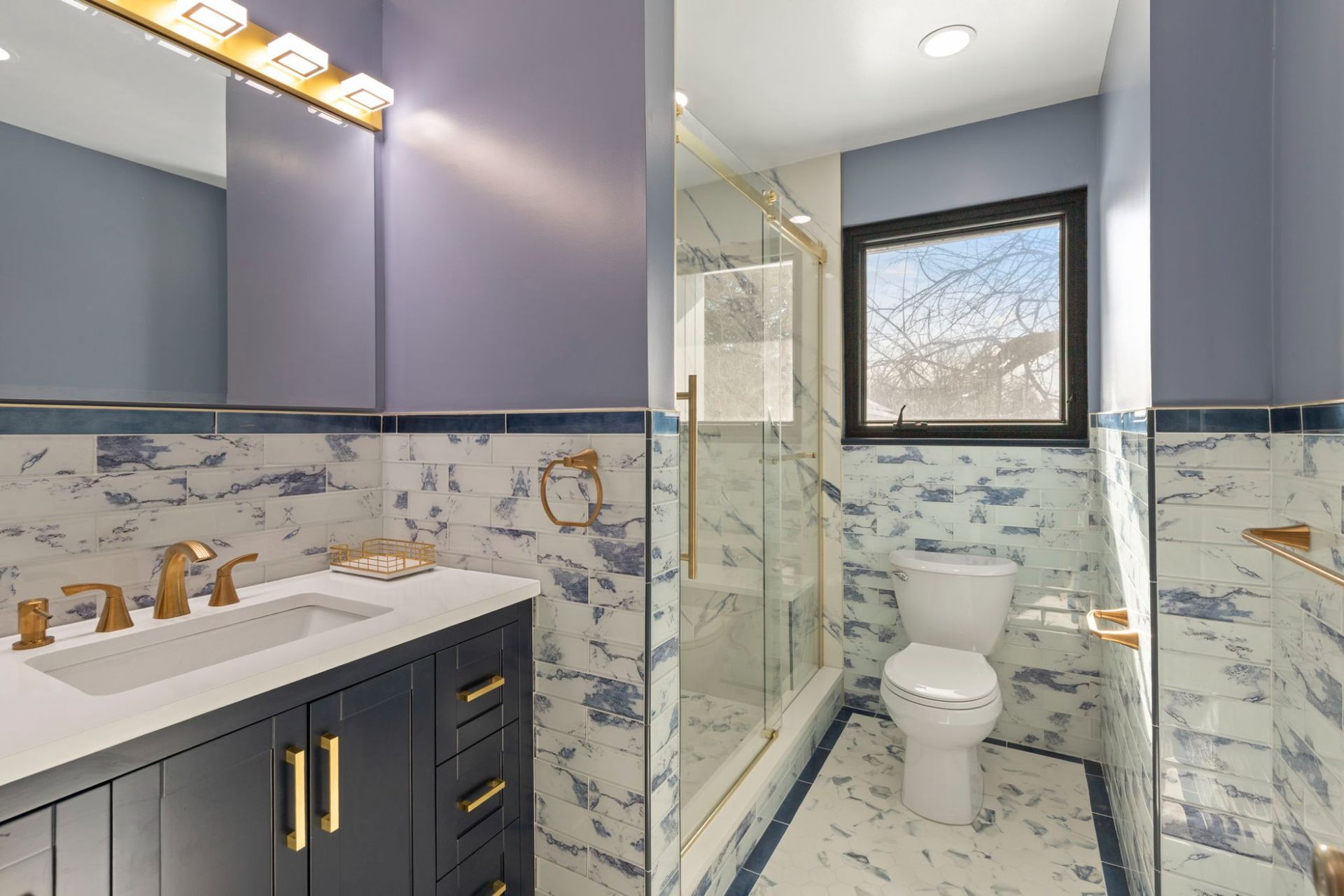 Complete bathroom renovation featuring navy blue vanity, glass walk-in shower, and marble tile by licensed remodeling contractor Handyman on Demand serving Clarksville MD
