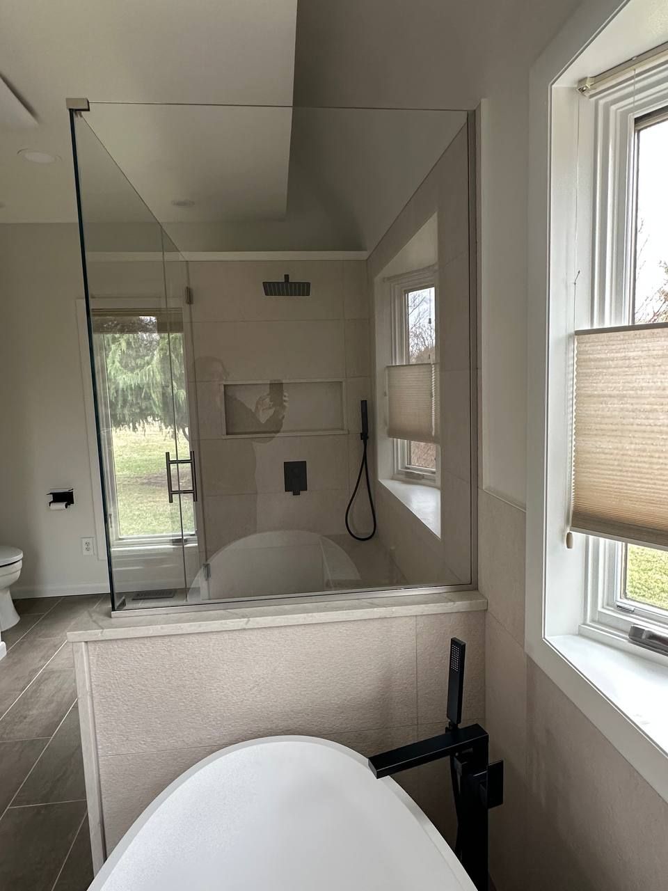 Custom bathroom remodel in Clarksville Maryland with frameless glass shower enclosure, rainfall shower head, freestanding soaking tub, and matte black fixtures by Handyman on Demand