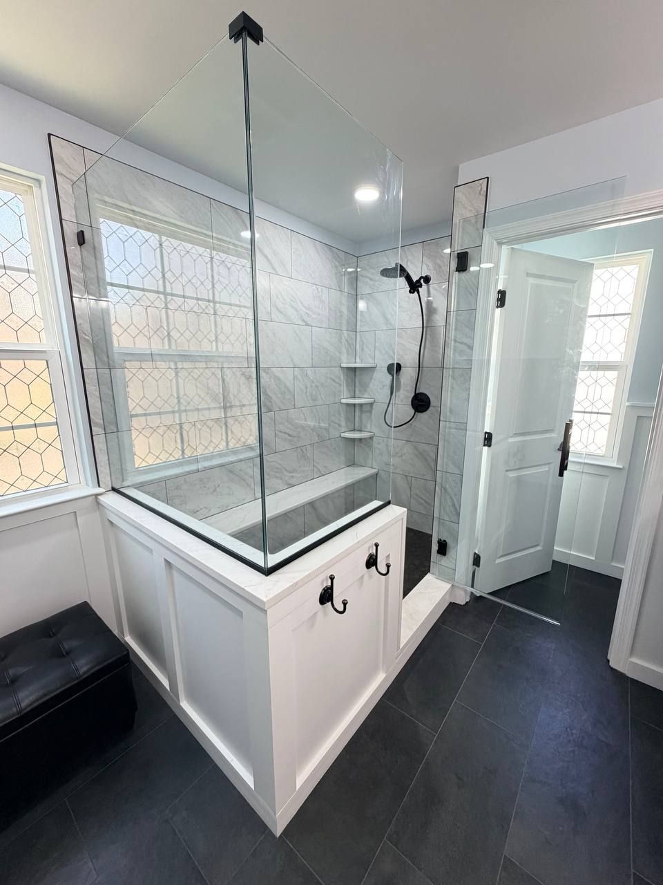Custom bathroom remodel and renovation in Clarksville MD with frameless glass shower enclosure, wainscoting knee wall, white marble tile surround, and matte black hardware by Handyman on Demand