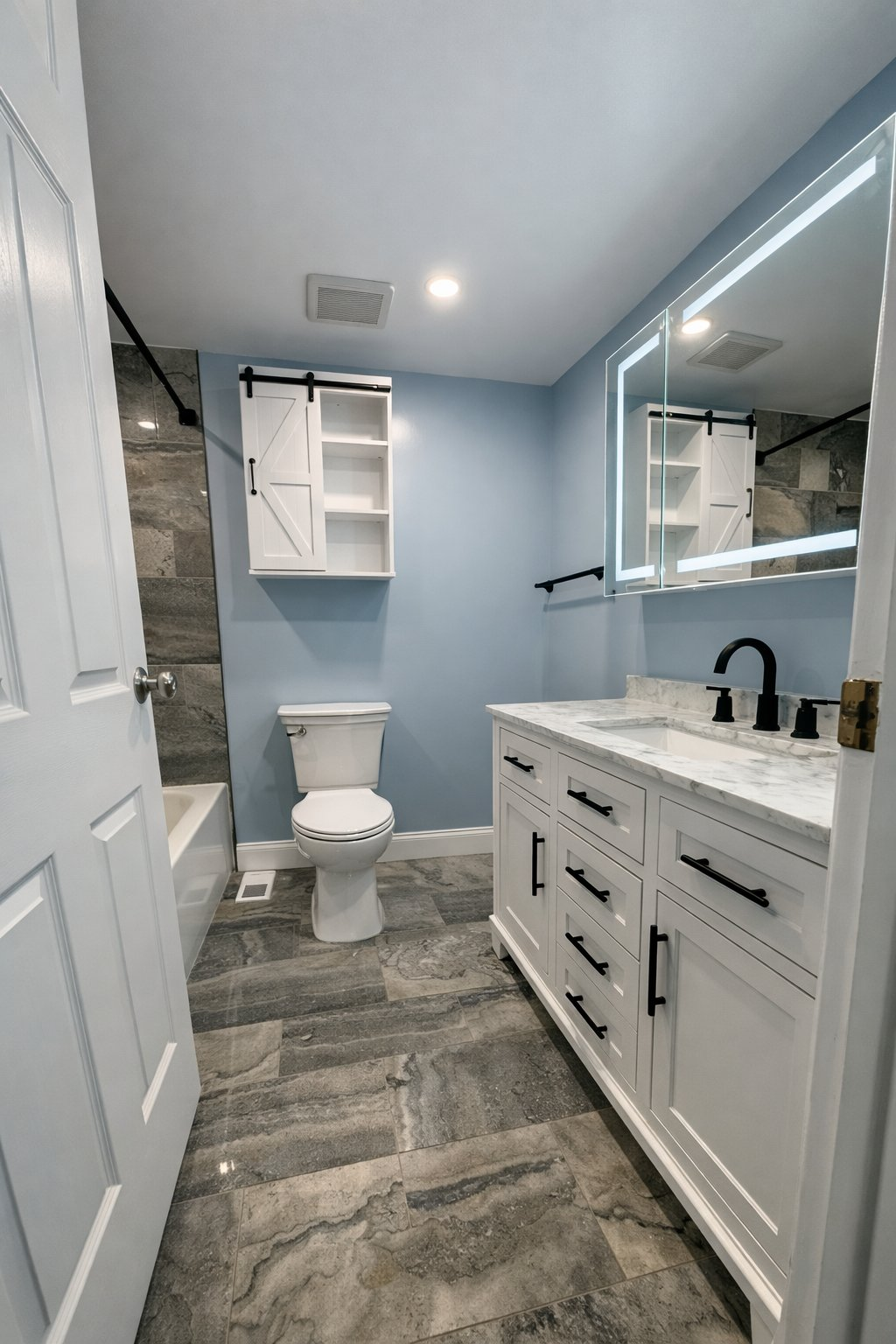 Full bathroom remodeling and renovation in Clarksville MD with white shaker vanity, marble countertop, LED backlit mirror, sliding barn door cabinet, and gray stone tile floor by Handyman on Demand