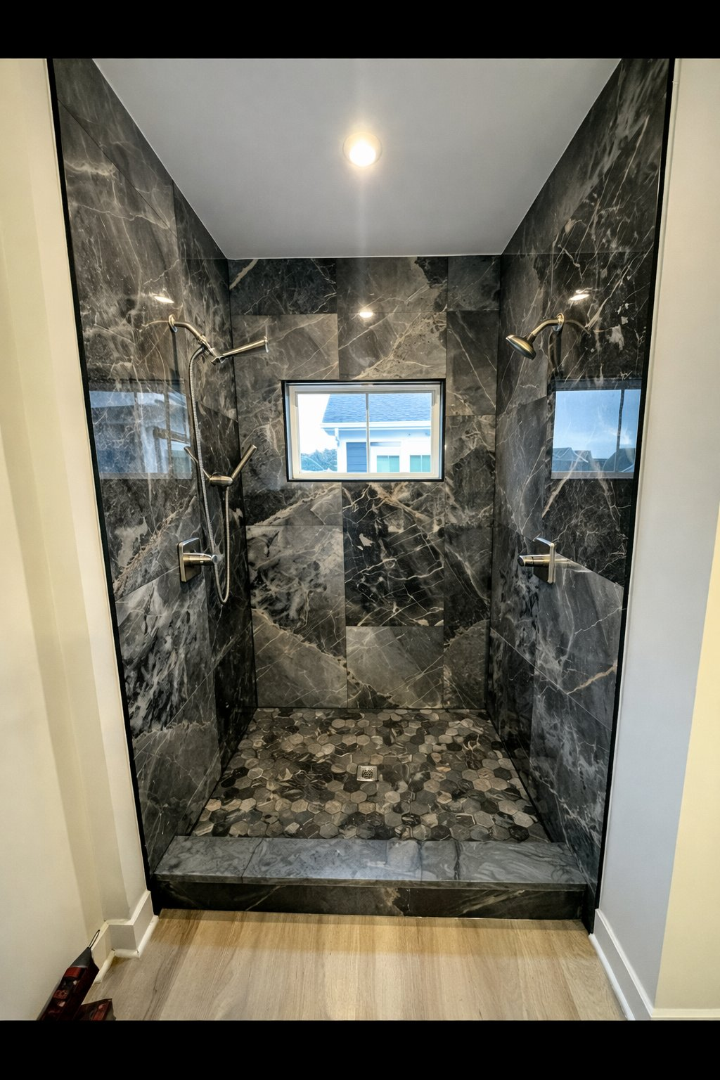 Luxury bathroom renovation and remodel in Clarksville MD featuring dramatic black marble tile double walk-in shower with dual shower heads and hex pebble stone floor by Handyman on Demand