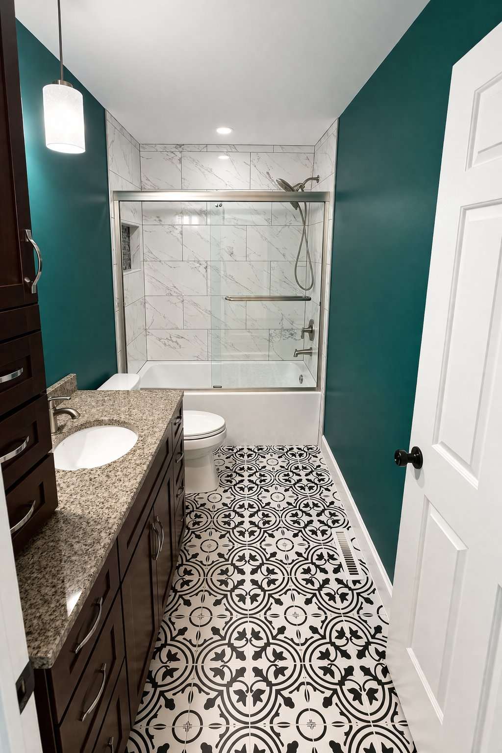 Master bathroom renovation in Clarksville MD featuring tub and shower combo, marble tile surround, bold decorative patterned floor tile, and teal accent wall by Handyman on Demand