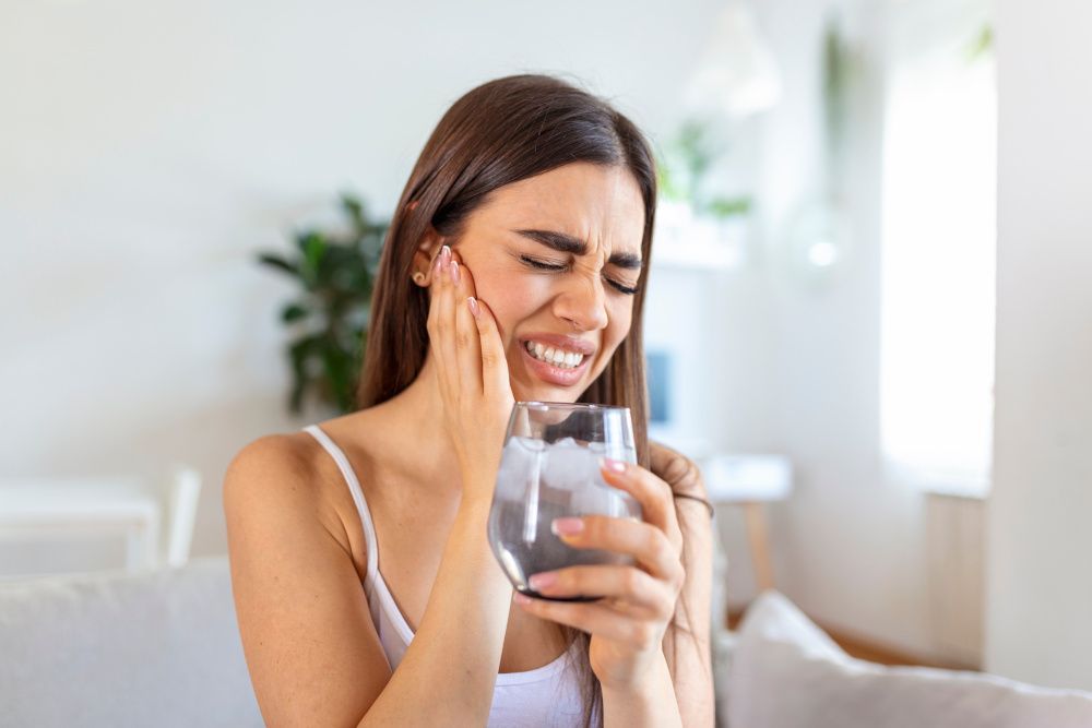 Graphicroyalty – stock.adobe.com Frau hat Zahnschmerzen beim Trinken von eiskaltem Wasser.