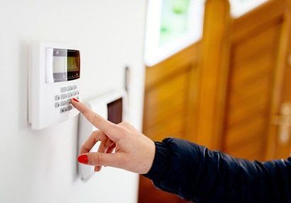 Mano che preme una tastiera di sicurezza bianca montata a parete in un corridoio