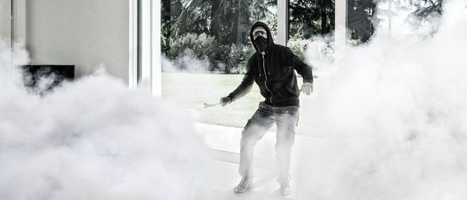 Persona che cammina in mezzo a una fitta coltre di fumo bianco o nebbia all'esterno di un edificio.