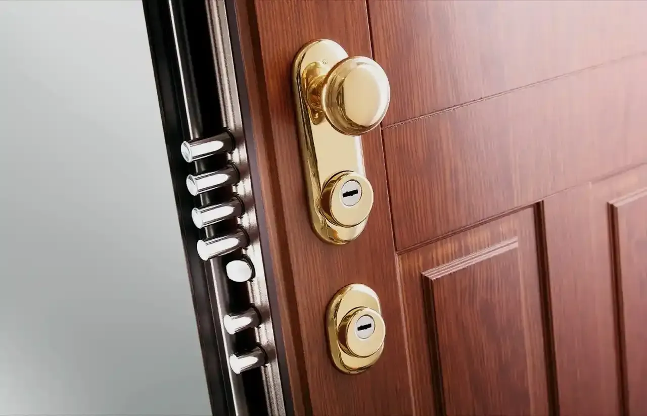 Primo piano di una porta d'ingresso in legno con serratura e maniglia in ottone.