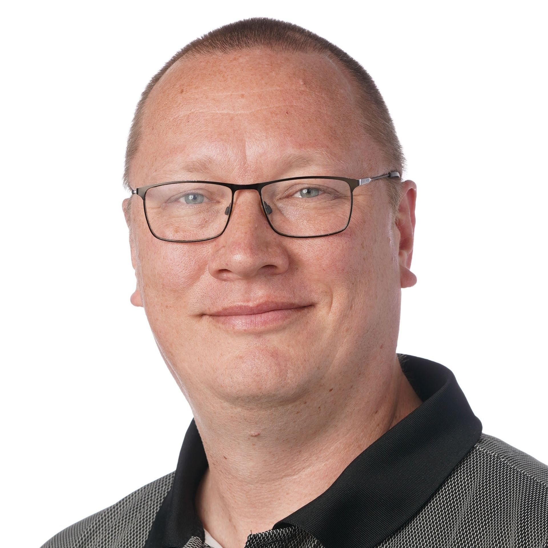 Mand med briller smilende, iført en mørk skjorte, mod en hvid baggrund.