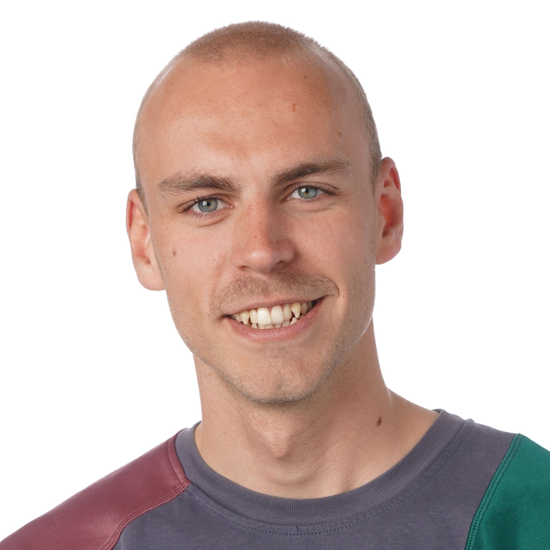 Mand med tyndt hår smiler, iført en orange og hvid skjorte, og ser på beskueren.
