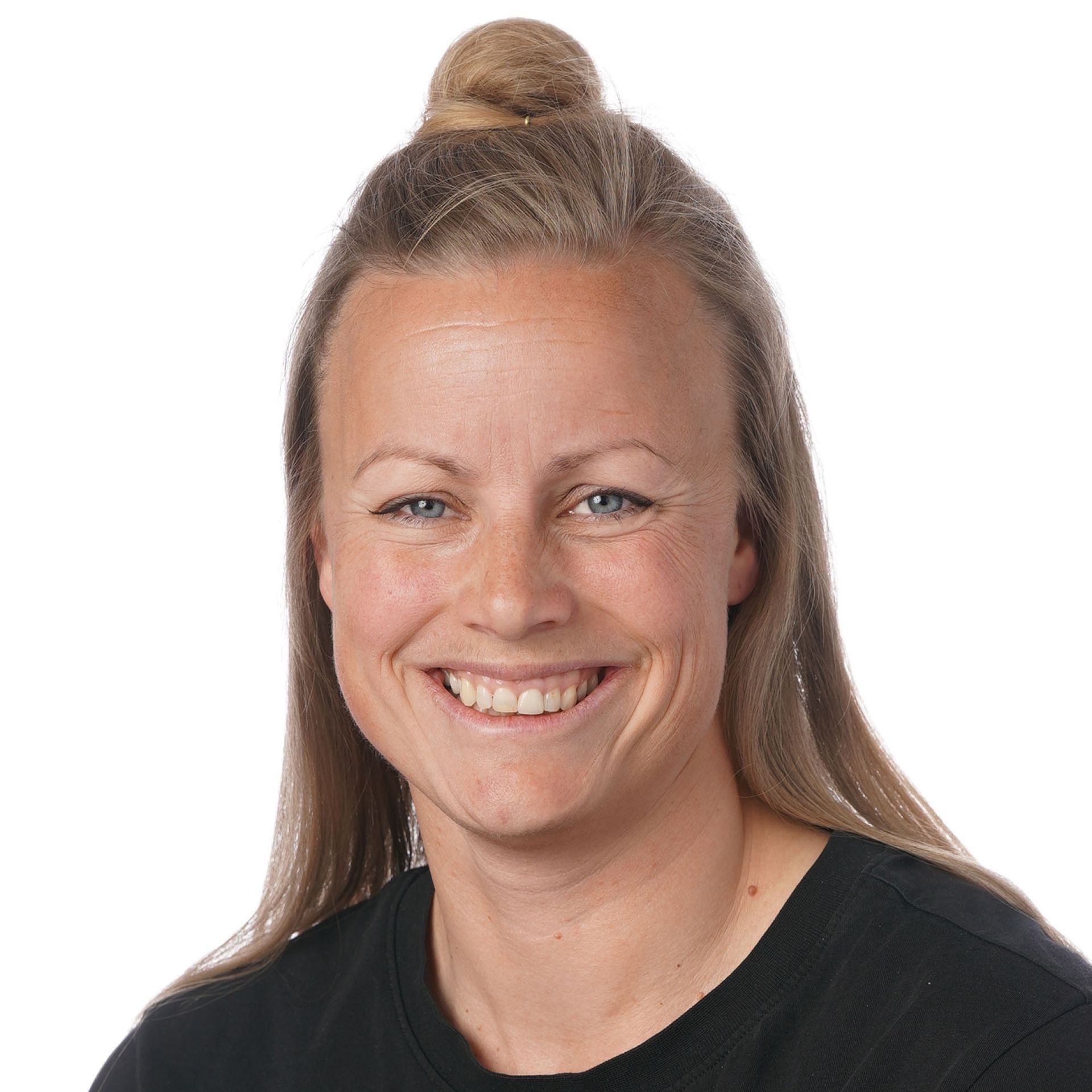 Smilende kvinde med hår i en knold, iført en sort top.