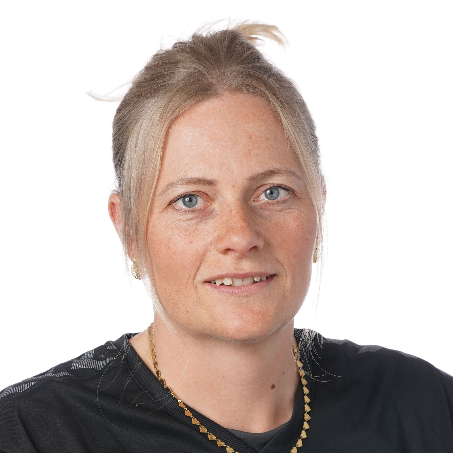 Kvinde med blond hår, der smiler, iført en sort skjorte, mod en hvid baggrund.