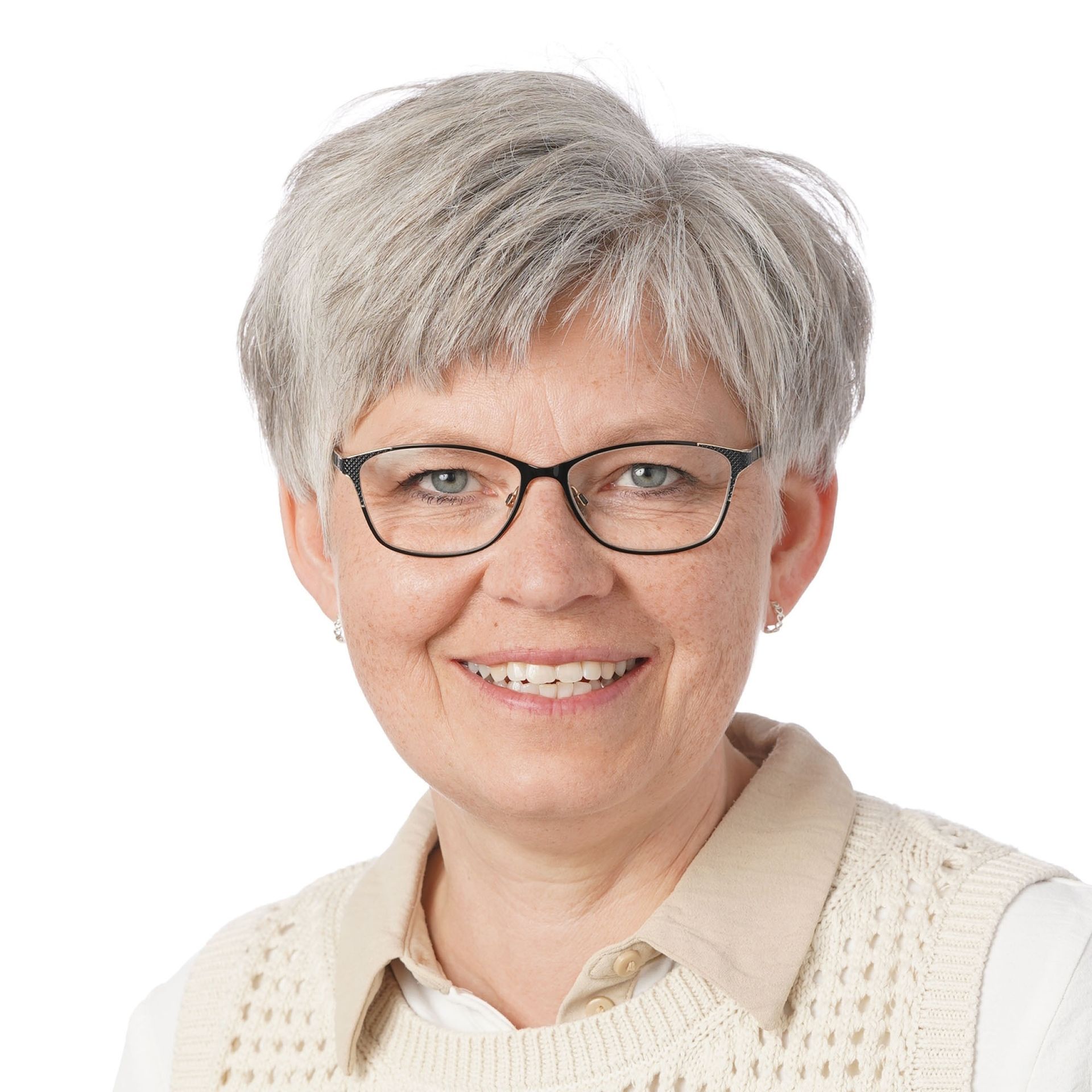 Kvinde med kort gråt hår og briller, iført en mørk blazer og blåt tørklæde, smilende.