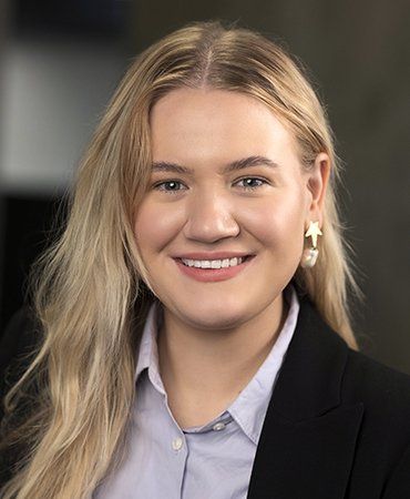 A woman wearing a suit and earrings is smiling for the camera.