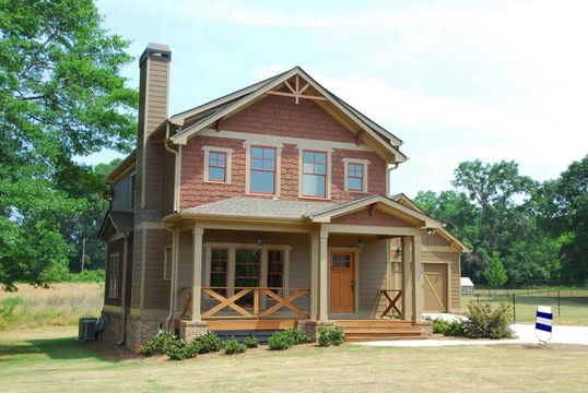 Two-story Craftsman home with a covered porch, brick chimney, and attached garage on a sunny day.