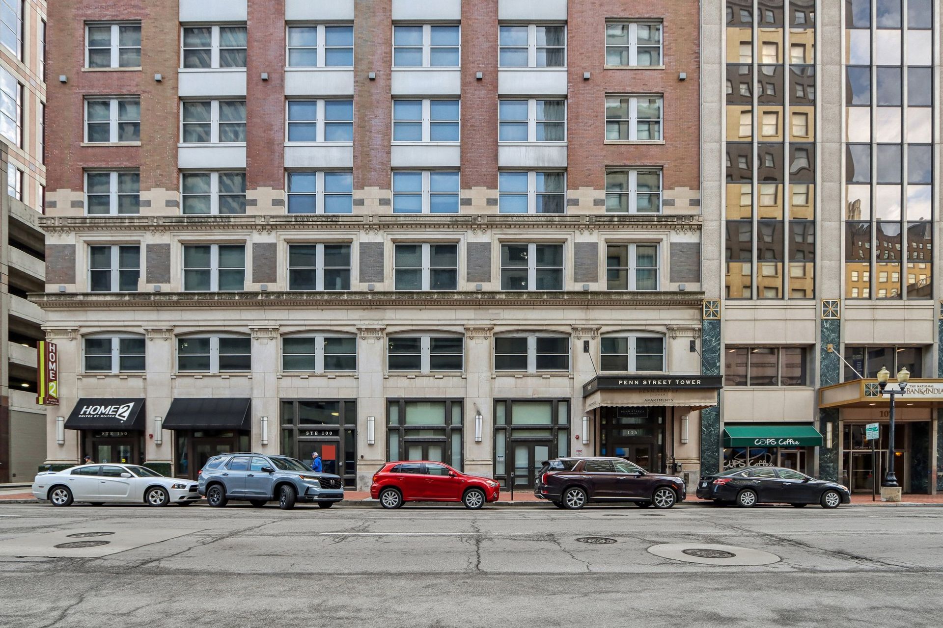 A row of cars are parked in front of a large building