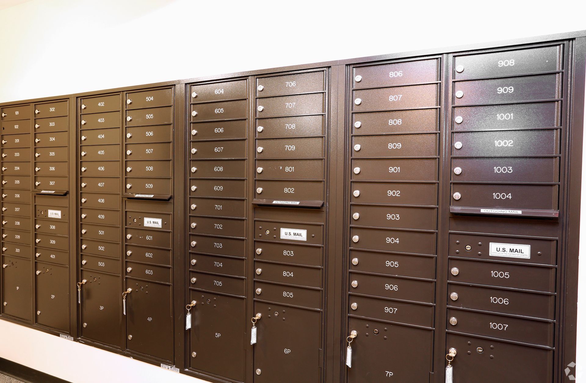 A row of mailboxes are lined up on a wall.