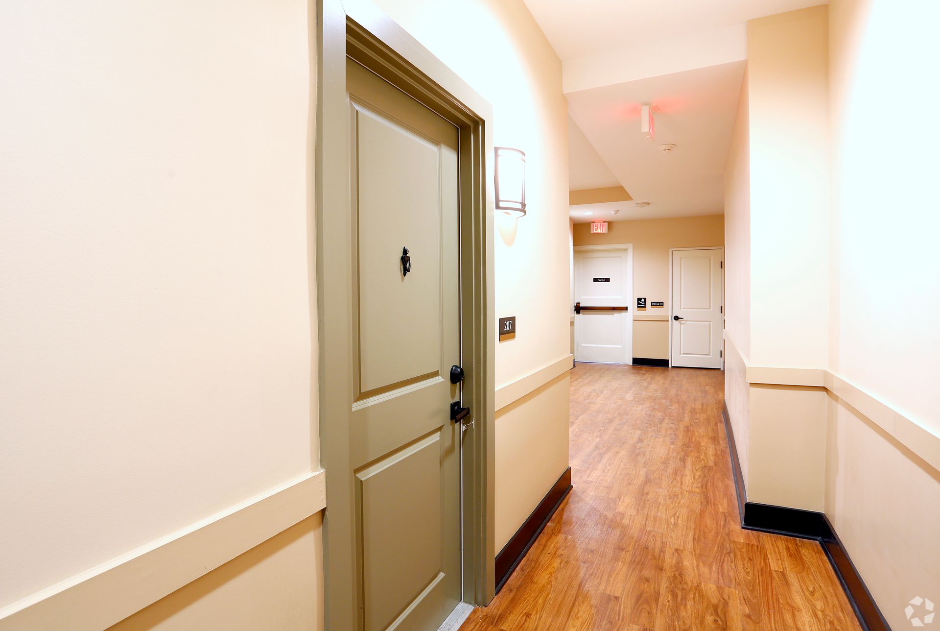 A long hallway with a door in the middle of it.