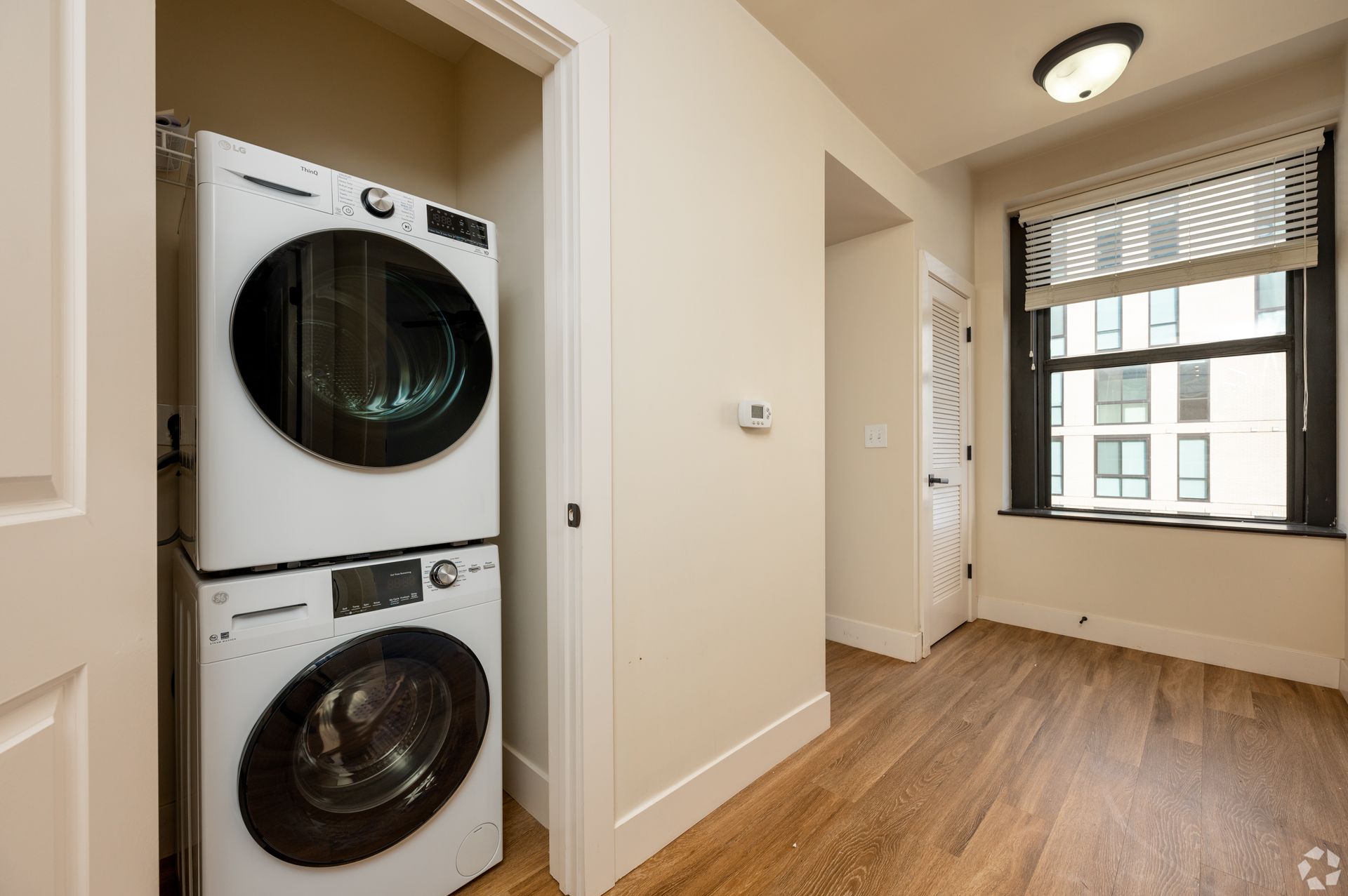 A washer and dryer are stacked on top of each other in a room next to a window.