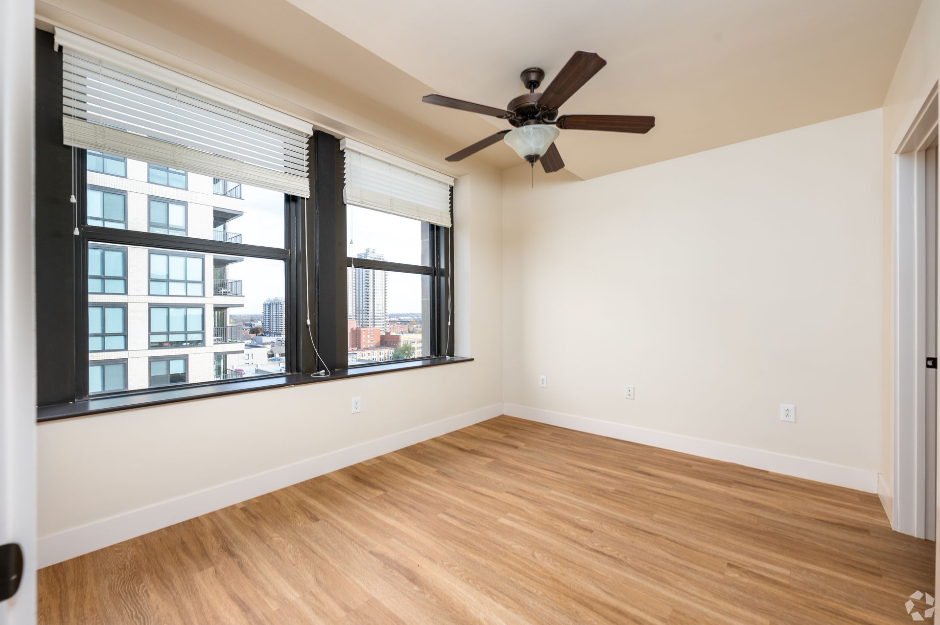 An empty room with hardwood floors and a ceiling fan