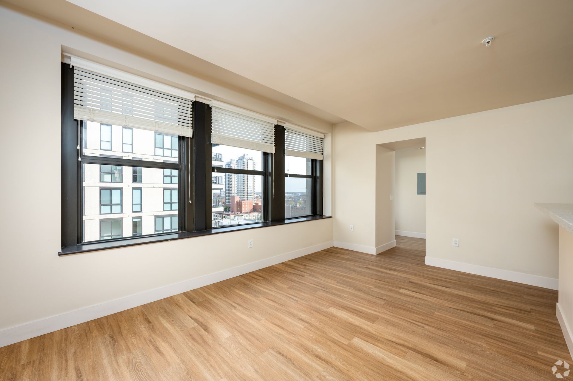 An empty living room with hardwood floors and a large window.