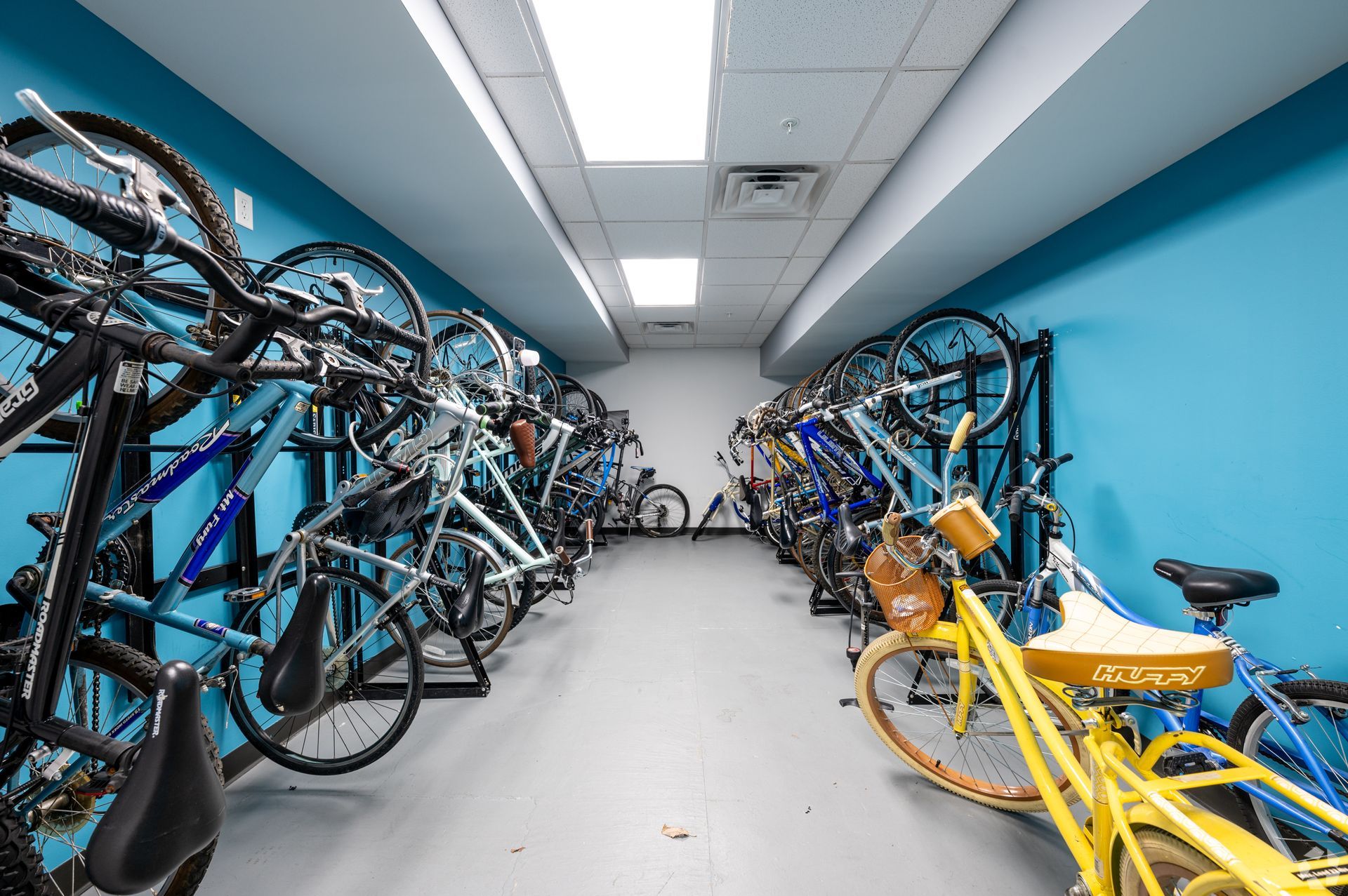 A bunch of bicycles are parked in a room with blue walls.