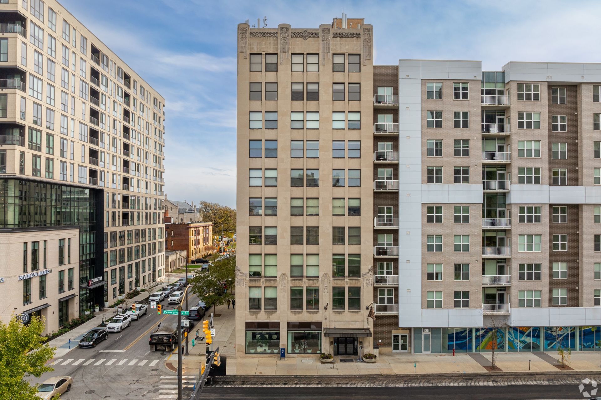 A large building with a lot of windows is next to a smaller building.