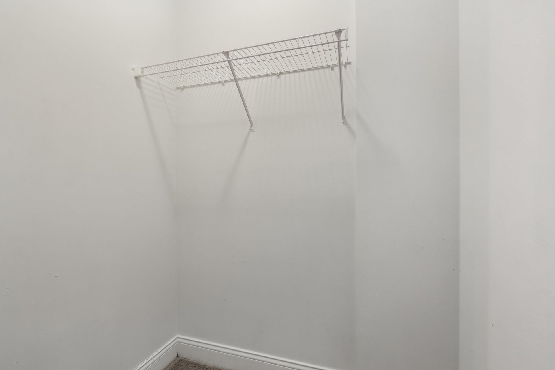 A walk in closet with a metal rack on the wall.
