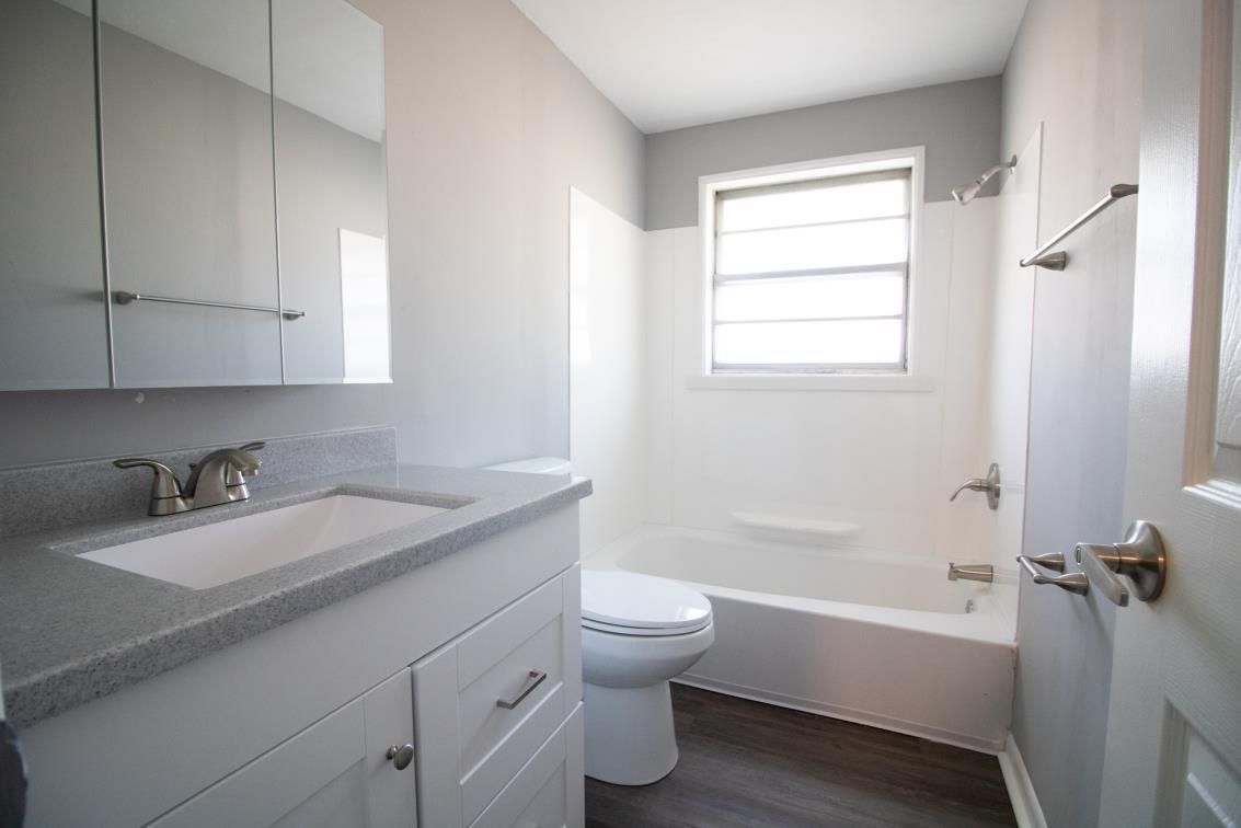 A bathroom with a sink , toilet , tub and window.
