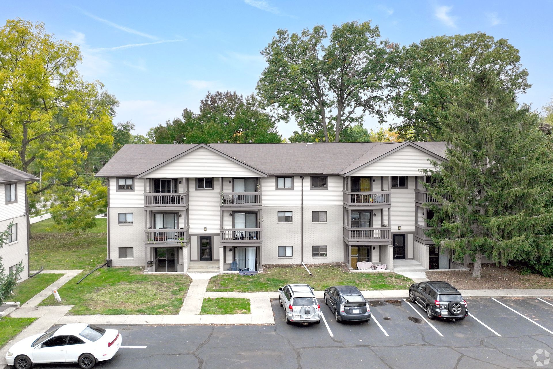 A large apartment building with cars parked in front of it.