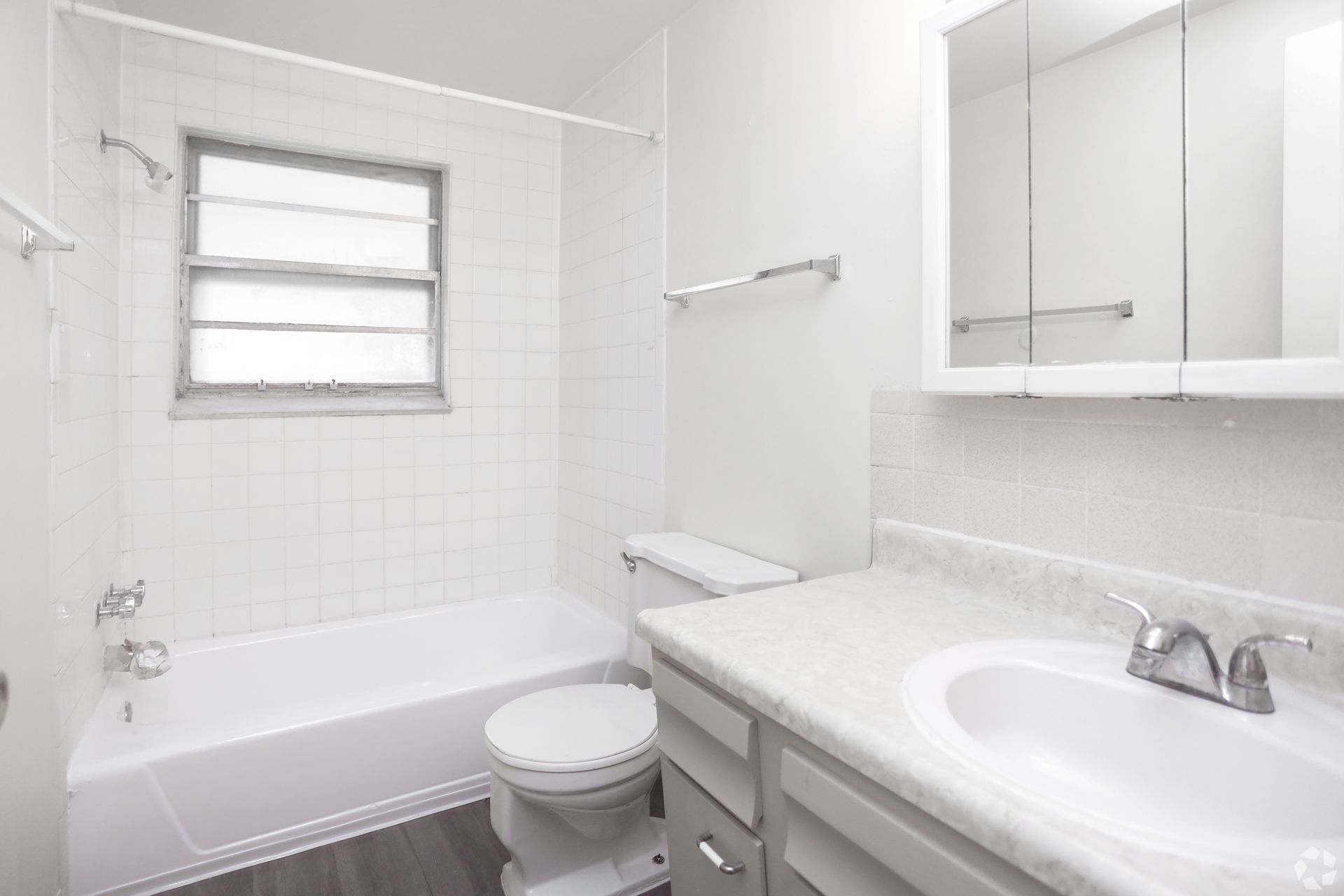 A bathroom with a tub , toilet , sink and mirror.